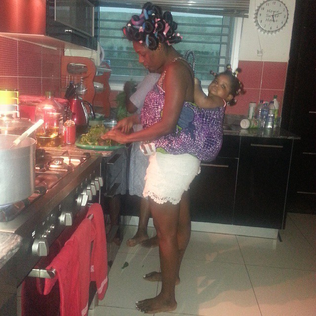Annie Idibia in her kitchen with baby Olivia tied to her back